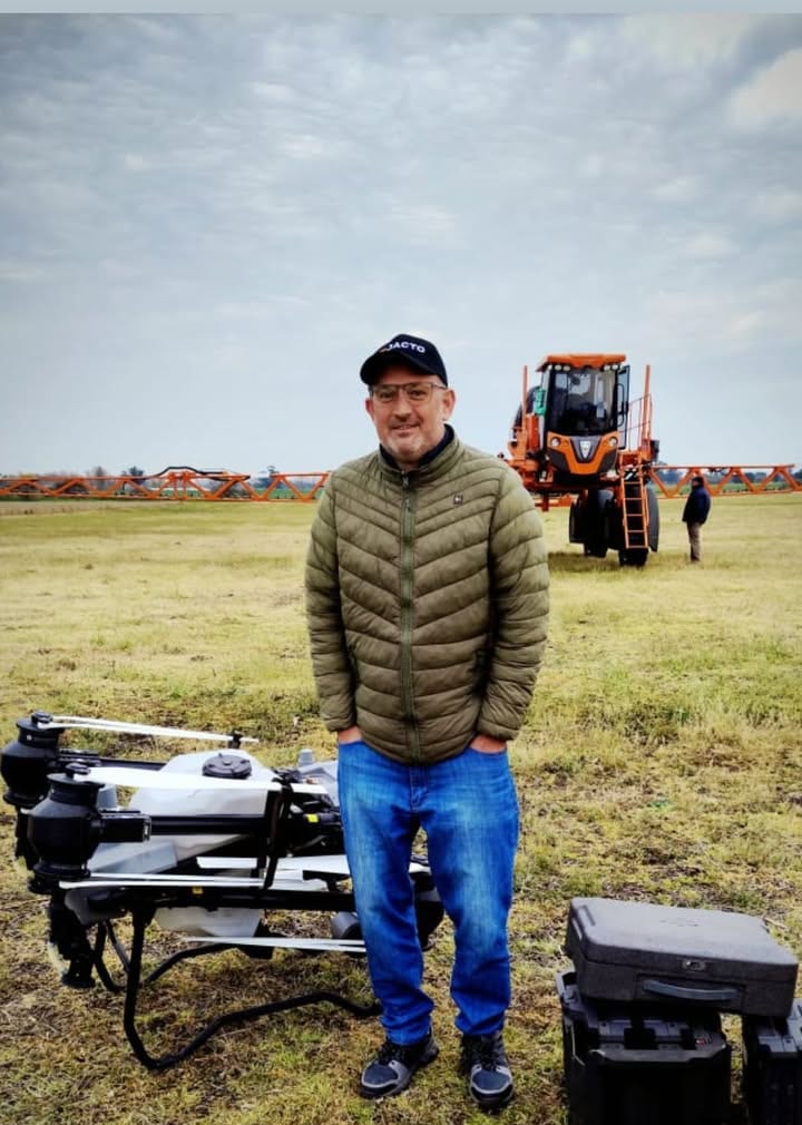 Integrante del equipo junto al drone y la pulverizadora en el campo